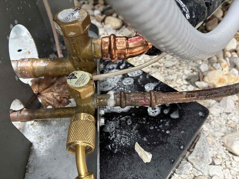 Responded to no-cooling call on recently installed AC unit. Upon arrival, performed diagnostic inspection and discovered severely corroded service valve and compromised refrigerant line connections. Replaced defective brass fittings, repaired copper line connections, and verified system pressures. Unit tested successfully and returned to normal operation.