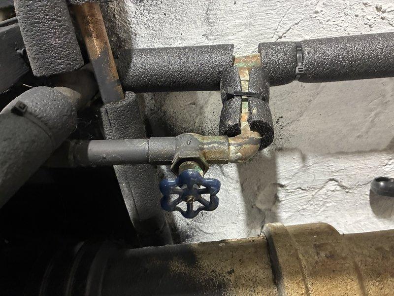 Responded to service call for leaking shut-off valve serving outdoor spigot. Upon inspection, identified the existing brass gate valve with blue wheel handle was failing at the packing nut, causing water seepage. Shut down water supply to the affected line and drained system. Removed deteriorated gate valve and replaced with new quarter-turn ball valve featuring brass body and white lever handle for improved reliability and ease of operation. Installed new copper fittings as needed to ensure proper connection integrity. Verified all joints were properly soldered and leak-free. Restored water supply and tested valve operation through multiple cycles. Confirmed no leaks at valve body, connections, or surrounding pipe insulation. System returned to full service with outdoor spigot functioning properly.