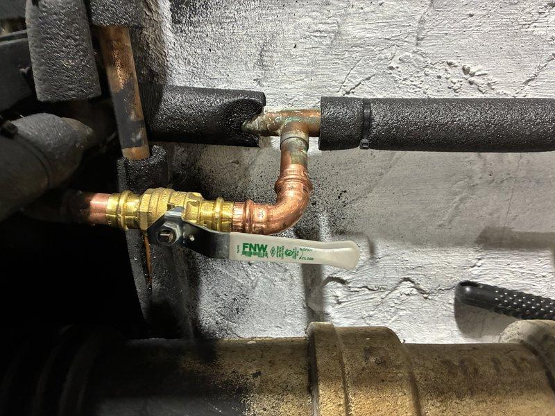 Responded to service call for leaking shut-off valve serving outdoor spigot. Upon inspection, identified the existing brass gate valve with blue wheel handle was failing at the packing nut, causing water seepage. Shut down water supply to the affected line and drained system. Removed deteriorated gate valve and replaced with new quarter-turn ball valve featuring brass body and white lever handle for improved reliability and ease of operation. Installed new copper fittings as needed to ensure proper connection integrity. Verified all joints were properly soldered and leak-free. Restored water supply and tested valve operation through multiple cycles. Confirmed no leaks at valve body, connections, or surrounding pipe insulation. System returned to full service with outdoor spigot functioning properly.