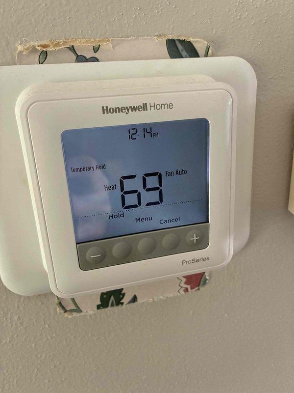 Completed comprehensive furnace and air conditioning tune-up service at residential property. Upon inspection, discovered significant frost and ice accumulation on the outdoor AC unit's evaporator coil, indicating potential refrigerant flow restriction, low charge, or airflow issues that require monitoring. Verified thermostat operation showing Honeywell ProSeries digital unit functioning properly in heat mode with temporary hold setting at 69°F. Noted debris accumulation around outdoor unit base that should be cleared to maintain proper airflow and system efficiency.