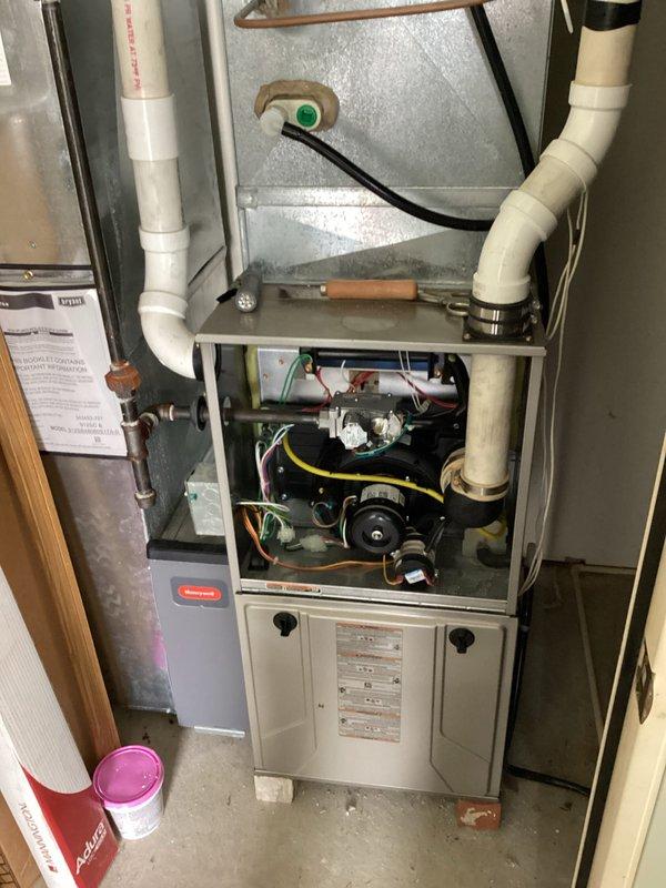 Responded to no heat call on residential furnace system over 10 years old. Upon arrival, accessed furnace cabinet and performed diagnostic inspection of blower motor assembly, electrical connections, and internal components. Verified system operation, checked all electrical connections including motor wiring and capacitor, inspected blower housing and motor mounting for proper function. Documented equipment condition with photos showing blower motor assembly, colored refrigerant lines with pressure fittings, and overall furnace installation including PVC venting and condensate drainage system. System restored to normal heating operation.