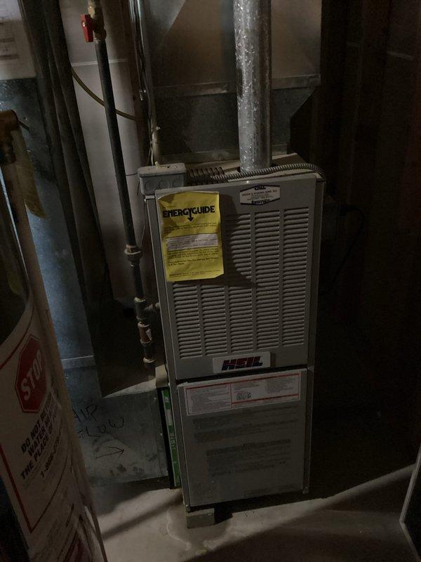 Responded to no cooling complaint on 10+ year old Heil HVAC system. Performed diagnostic evaluation of furnace and air conditioning components in basement mechanical room. Documented existing equipment condition with photographs showing unit age and wear consistent with decade-plus operation, noting visible Energy Guide labeling and manufacturer specifications for service reference.