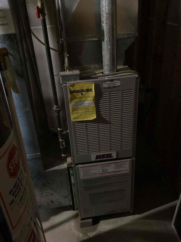 Responded to no cooling complaint on 10+ year old Heil HVAC system. Performed diagnostic evaluation of furnace and air conditioning components in basement mechanical room. Documented existing equipment condition with photographs showing unit age and wear consistent with decade-plus operation, noting visible Energy Guide labeling and manufacturer specifications for service reference.