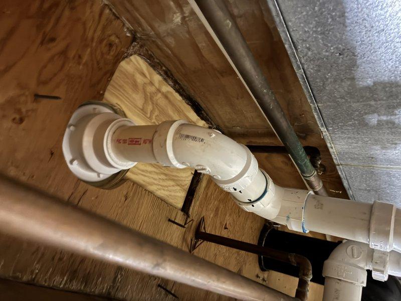 Completed shower drain replacement in residential bathroom. Accessed drain assembly through crawl space, removed existing worn drain components, and installed new white PVC drain piping with proper fittings and connections to existing waste line. Verified proper slope and secure mounting of all drain components. Tested system for leaks and confirmed proper drainage flow through basin strainer assembly.