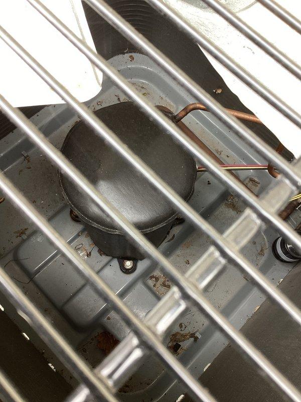 Responded to no cooling complaint on residential split system air conditioning unit. Upon arrival, found outdoor condenser unit running with fan motor operational but system not producing cold air. Performed diagnostic inspection of condenser components through top access panel, verified fan motor operation and checked for proper compressor function. Unit remains under parts and labor warranty coverage.