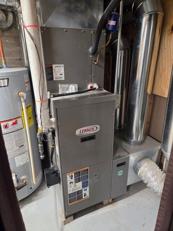 Responded to no cooling complaint on Lennox HVAC system. Performed diagnostic evaluation of outdoor condensing unit and indoor furnace/air handler. Documented equipment model information and captured installation photos showing complete system layout including outdoor unit on concrete pad with electrical disconnect, indoor furnace with associated ductwork, and all mechanical connections. System is over 10 years old with vegetation growth around outdoor unit noted during inspection.