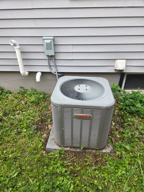 Responded to no cooling complaint on Lennox HVAC system. Performed diagnostic evaluation of outdoor condensing unit and indoor furnace/air handler. Documented equipment model information and captured installation photos showing complete system layout including outdoor unit on concrete pad with electrical disconnect, indoor furnace with associated ductwork, and all mechanical connections. System is over 10 years old with vegetation growth around outdoor unit noted during inspection.
