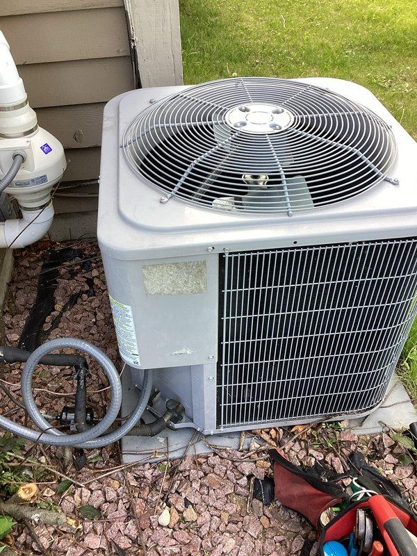 Responded to no cooling complaint on residential air conditioning system. Upon arrival, discovered refrigerant line set had been physically damaged during recent landscaping activities, resulting in complete refrigerant loss from the system. Inspected outdoor condensing unit and traced refrigerant lines to identify extent of damage. Found compromised section of line set where landscape work had impacted the copper tubing, causing puncture and subsequent leak. Documented equipment information and damage with photographs showing affected refrigerant lines, insulation, and outdoor unit positioning. System was rendered inoperable due to complete loss of refrigerant charge from damaged line set requiring repair or replacement of affected section and system recharge.