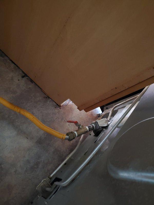 Completed diagnostic inspection for new gas line installation behind stove range. Assessed existing yellow flexible gas line routing and connection points in mechanical space, verified proper shut-off valve placement requirements, and documented current plumbing configuration including PVC piping and wall conditions to determine feasibility for same-day installation of new gas line with dedicated shut-off valve per customer request.