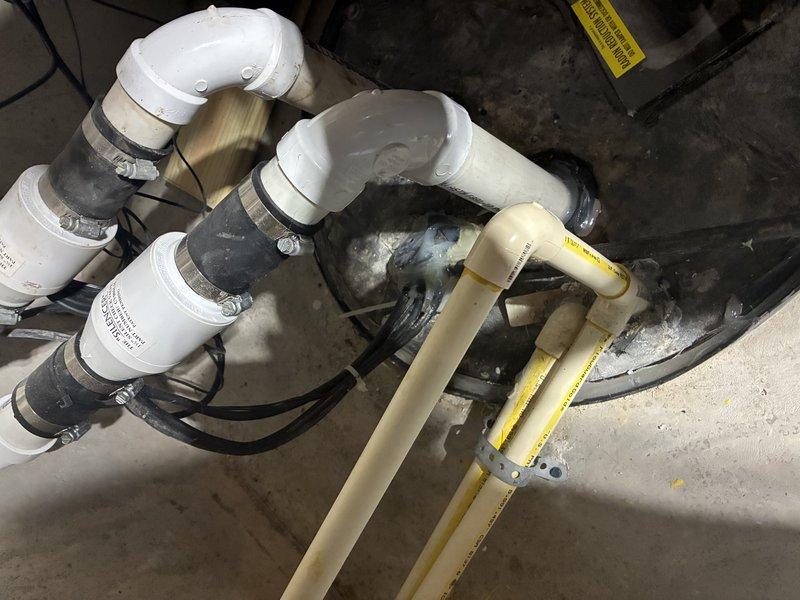 Completed diagnostic evaluation of existing radon mitigation system and assessed sump pump configuration in basement utility area. Inspected white PVC drainage piping with multiple elbow connections and verified proper installation of metal hose clamps at connection points. Evaluated current sump pump system and provided recommendations for new sump pump installation along with battery backup system to ensure continuous operation during power outages. Additionally assessed water softener system and discussed magnesium anode rod replacement options to extend equipment lifespan and maintain water quality.