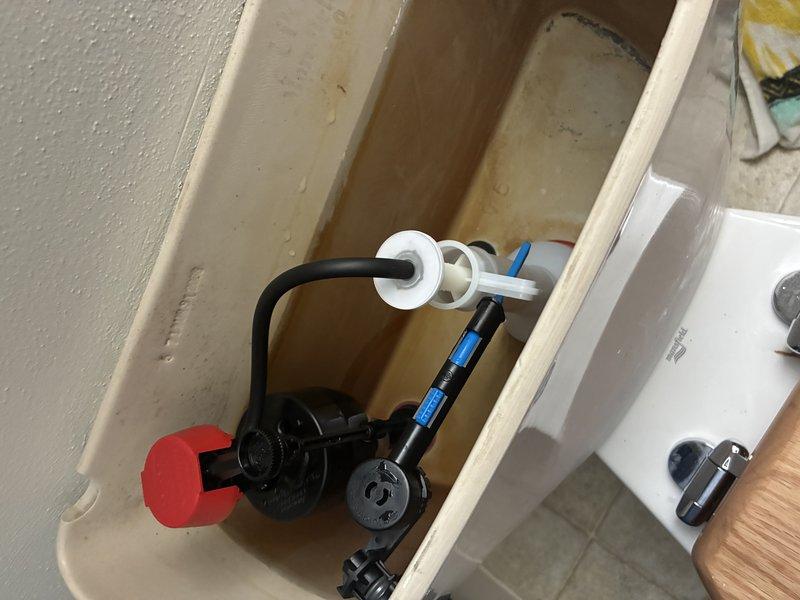 Completed installation of replacement flush valve and fill valve assembly in residential toilet. Removed existing worn components and installed new black fill valve with float mechanism and refill tube assembly, along with new flush valve system featuring white and blue plastic components. All connections were secured and tested for proper operation and water flow. Tank was refilled and system cycled multiple times to verify proper flush function, fill cycle timing, and water shut-off at appropriate level. No leaks detected upon completion of installation.