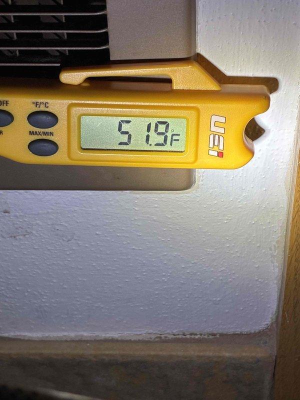 Completed rescheduled system start-up following previous cold weather delay. Verified refrigerant charge levels and measured system temperatures, confirming proper operation with suction line temperature reading at 51.9°F. Inspected refrigerant line connections and penetrations through cabinet structure, ensuring all fittings and seals were secure with no visible leaks or defects.