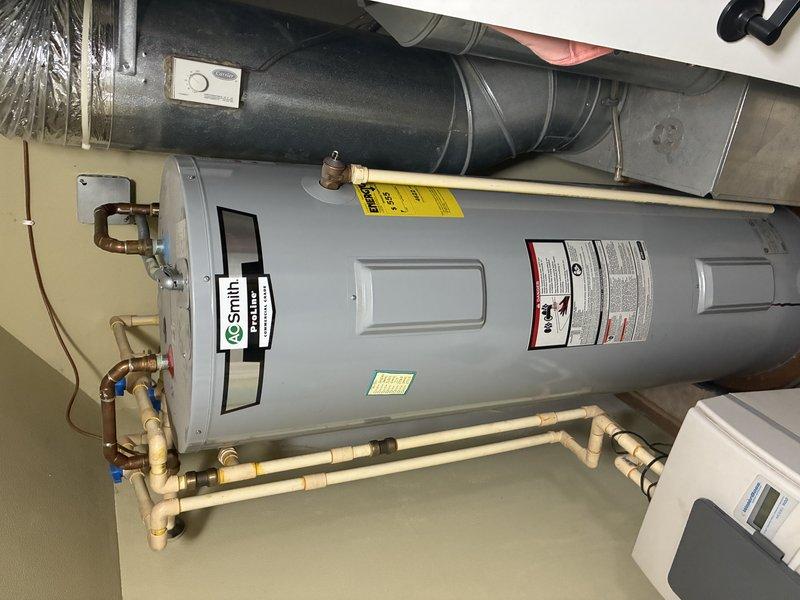Responded to service call regarding rusty water observed beneath water heater. Upon arrival, performed comprehensive diagnostic inspection of A.O. Smith electric storage tank water heater (Model ENT-50, 50-gallon capacity, 4500-watt, 240-volt unit). Thoroughly examined tank exterior, all plumbing connections, copper and PVC piping, brass fittings, shut-off valves, and pressure relief valve for signs of active leakage or corrosion. Inspected floor area surrounding base of unit for moisture accumulation and traced potential sources of discoloration. Documented equipment condition and connection integrity with photographic evidence showing current installation configuration and manufacturer specifications.