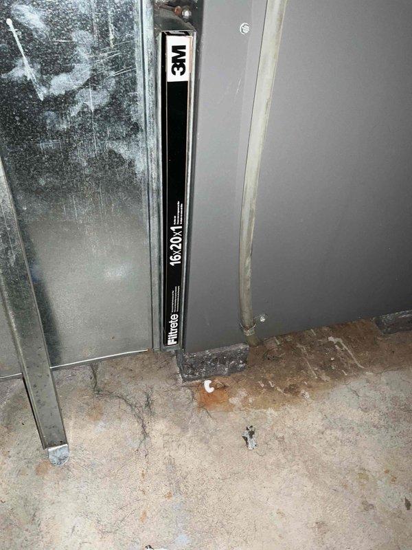 Conducted on-site evaluation of existing HVAC air handler system located in basement utility space and provided replacement estimate. Documented current equipment configuration including vertical air handler unit with 16x20x1 filter specifications, associated metallic ductwork showing dust accumulation and surface staining, and overall mechanical room layout with water heater and existing utility infrastructure. Assessed installation environment including concrete floor conditions, exposed ceiling joists, and existing duct routing to determine replacement specifications and system requirements.