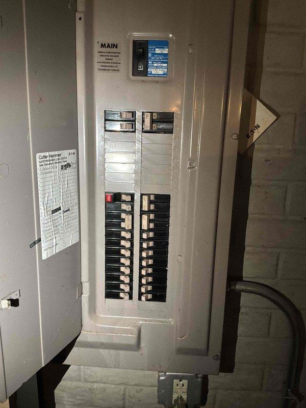 Conducted comprehensive site assessment for complete air conditioning system replacement at residential property with forced air furnace system in basement. Evaluated existing Trane XE 1000 outdoor condensing unit positioned on concrete pad against perimeter fence, noting unit failure and need for full system replacement. Assessed refrigerant line routing, electrical service panel capacity and circuit breaker configuration, and existing infrastructure to determine equipment specifications and installation requirements for new HVAC system replacement.