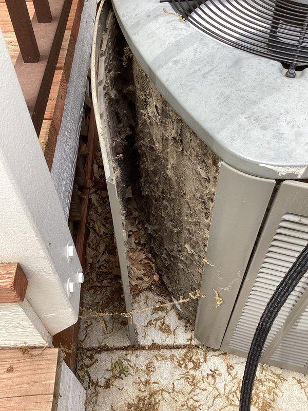 Responded to no cooling complaint on residential air conditioning system. Upon arrival, found outdoor condenser unit with significant debris accumulation in and around equipment, restricting airflow to coil. Performed diagnostic evaluation and cleared accumulated leaves, twigs, and organic matter from unit perimeter and between equipment and deck structure. Inspected refrigerant lines, electrical connections, and condenser operation. Unit restored to proper cooling operation after removing airflow restrictions and verifying system performance.