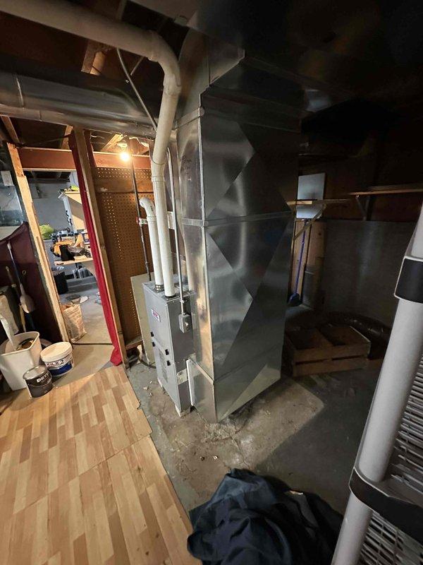 Conducted estimate for air conditioning system installation to existing natural gas furnace setup in basement location. Assessed current HVAC equipment configuration, including existing furnace unit with diamond-textured exterior panels and PVC venting system, to determine compatibility and requirements for adding cooling capacity. Evaluated available space, electrical service, condensate drainage options, and ductwork modifications needed to integrate new AC system with existing heating infrastructure.
