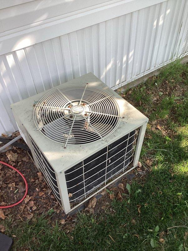 Responded to no cooling complaint on aging residential air conditioning system. Upon arrival, performed diagnostic inspection of outdoor condenser unit, which showed signs of age with dirt and debris accumulation on top surface and dusty mesh grille panels. Documented equipment condition with photographs for service records. Unit appeared operational but required thorough assessment to determine cause of cooling failure.