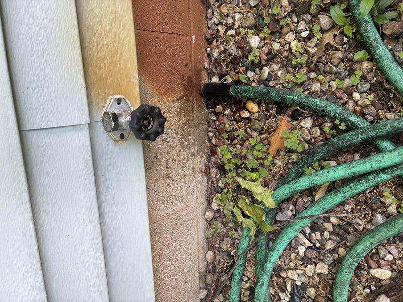 Responded to service call for leaking outdoor hose bib. Upon inspection, confirmed the exterior spigot mounted on the building's foundation was compromised due to internal rust buildup causing water seepage. Accessed the supply line from the interior crawl space and installed a new quarter-turn ball valve with red handle for improved shut-off control. Replaced the exterior hose bib with new chrome fixture, ensuring proper seal against the vinyl siding to prevent future leaks.