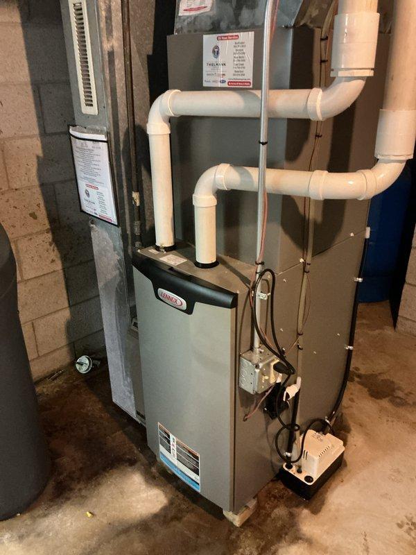Responded to AC leaking complaint in basement and performed warranty inspection of Lennox furnace system installed approximately one year prior. Upon arrival, inspected condensate drainage system including pump assembly and PVC discharge lines. Verified proper operation of condensate pump, checked drain line routing and confirmed no blockages in primary or secondary drain paths. Examined all pipe connections and fittings for leaks or improper sealing. System found to be operating within normal parameters with no active leaks detected at time of inspection.