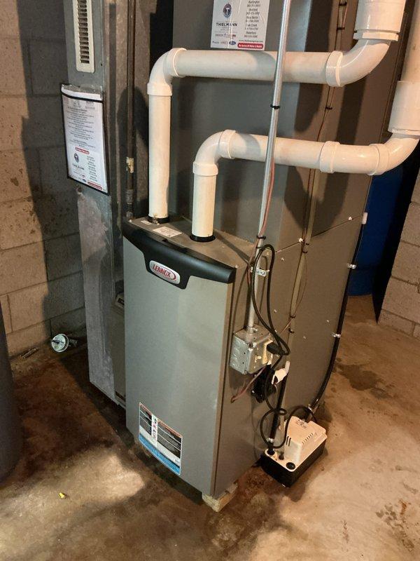 Responded to AC leaking complaint in basement and performed warranty inspection of Lennox furnace system installed approximately one year prior. Upon arrival, inspected condensate drainage system including pump assembly and PVC discharge lines. Verified proper operation of condensate pump, checked drain line routing and confirmed no blockages in primary or secondary drain paths. Examined all pipe connections and fittings for leaks or improper sealing. System found to be operating within normal parameters with no active leaks detected at time of inspection.