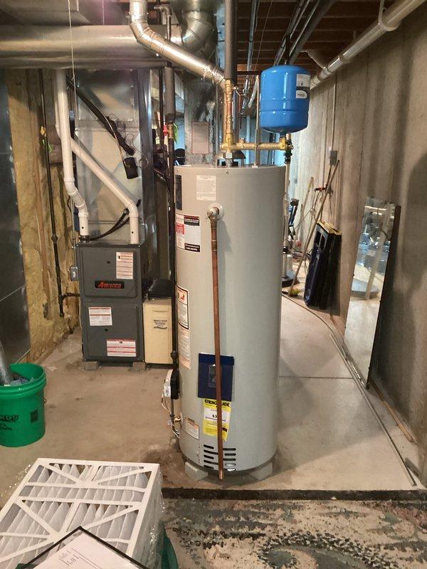 Installed a 40-gallon standard atmospheric vent water heater in basement mechanical room with associated copper supply piping, draft hood, and metallic vent connector. Blue expansion tank was mounted on cold water supply line, and all connections were completed per manufacturer specifications without requiring permit or electrical modifications.