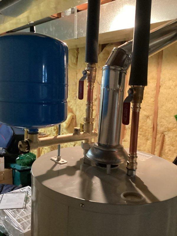 Installed a 40-gallon standard atmospheric vent water heater in basement mechanical room with associated copper supply piping, draft hood, and metallic vent connector. Blue expansion tank was mounted on cold water supply line, and all connections were completed per manufacturer specifications without requiring permit or electrical modifications.