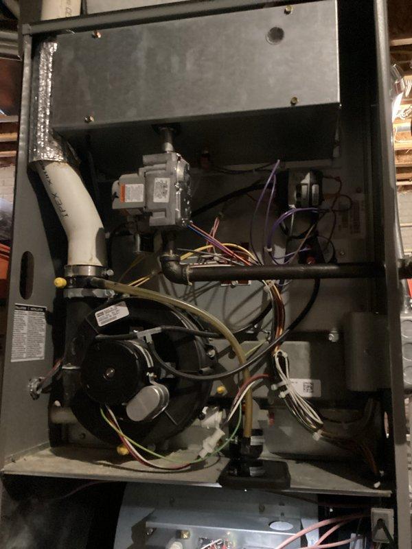 Responded to no heat call on residential furnace system over 10 years old. Upon arrival, performed diagnostic inspection of unit with access panel removed to assess internal components. Inspected blower motor assembly, electrical connections, gas valve mechanisms, and control wiring. Examined condition of cylindrical blower motor, verified wire connections including multiple colored leads secured with zip ties, and assessed overall system functionality. Documented internal component condition including PVC condensate/vent line, metal housing integrity, and mounting hardware. System restored to proper operation following diagnostic service.