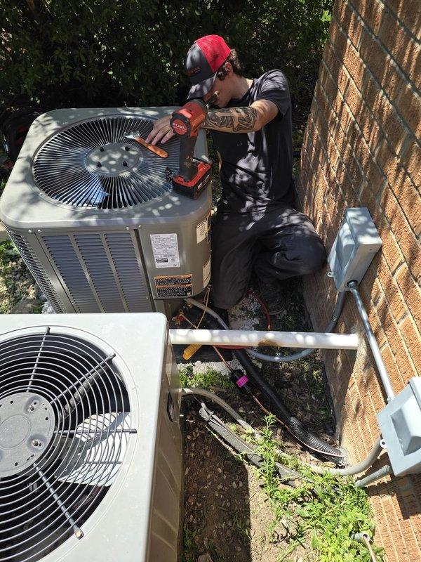 Completed full HVAC system replacement including outdoor condensing unit and associated components. Technician performed installation of new air conditioning condenser unit, removed existing equipment, secured all electrical connections at disconnect box, and verified proper operation of fan assembly and mechanical components in outdoor service area adjacent to building exterior.