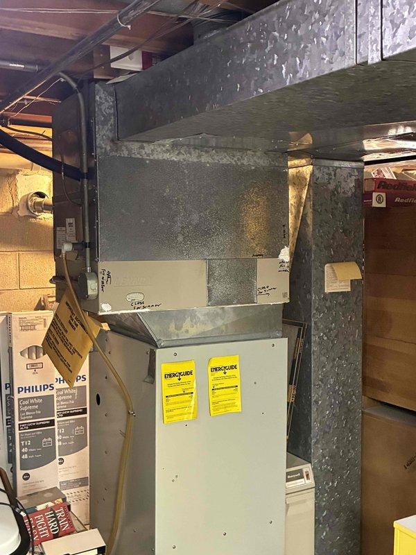 Provided comprehensive estimate for complete HVAC system replacement on aging 30+ year old air conditioning and heating equipment. Unit remains operational but has exceeded its expected service life, with previous contractor recommending full system replacement. Evaluated existing furnace/air handler installation in basement mechanical room, noting aged ductwork with visible deterioration and discoloration. Documented current system configuration including metal furnace unit with overhead supply ductwork and assessed accessibility for replacement equipment installation.