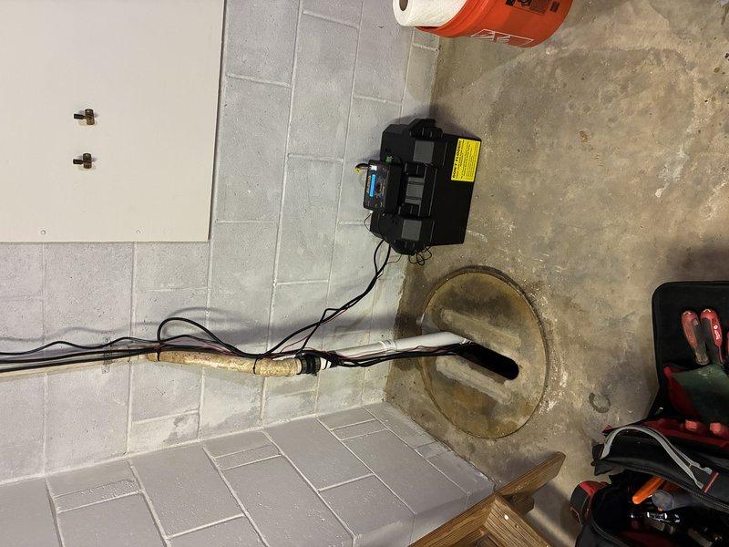 Completed installation of battery backup sump pump system in basement utility area. Installed new sump pump unit with battery backup capability in existing basin, configured float switch and control unit, and mounted backup controller on wall above basin. Verified proper operation of primary pump, battery backup system, and all electrical connections to ensure reliable water removal during power outages.