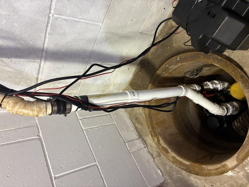 Completed installation of battery backup sump pump system in basement utility area. Installed new sump pump unit with battery backup capability in existing basin, configured float switch and control unit, and mounted backup controller on wall above basin. Verified proper operation of primary pump, battery backup system, and all electrical connections to ensure reliable water removal during power outages.