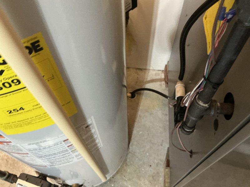 Completed comprehensive HVAC system evaluation for air conditioning replacement estimate at residential property. Assessed existing outdoor cylindrical condenser unit showing weather-related wear and indoor furnace/air handler equipment located in utility area alongside water heater. Documented current system configuration including electrical connections, refrigerant line routing, condensate drainage, and equipment placement on exterior concrete pad with landscaping considerations. Photographed both indoor and outdoor components to provide detailed equipment specifications and installation parameters for replacement system proposal.