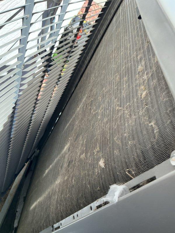 Completed preventative maintenance tune-up on residential air conditioning system. Inspected outdoor condensing unit, noting moderate dust and debris accumulation on condenser coil fins that could impact heat transfer efficiency. Documented current condition of unit components including coil surfaces, cabinet housing, and protective grilles for maintenance records.