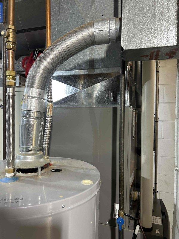 Completed installation of new air conditioning system with evaporator coil in residential basement utility area. System includes new air handler unit positioned vertically with proper clearances for maintenance access, connected to existing ductwork via flexible aluminum ducting with appropriate elbow configurations. All refrigerant lines, electrical connections, and condensate drainage installed to manufacturer specifications and local code requirements.