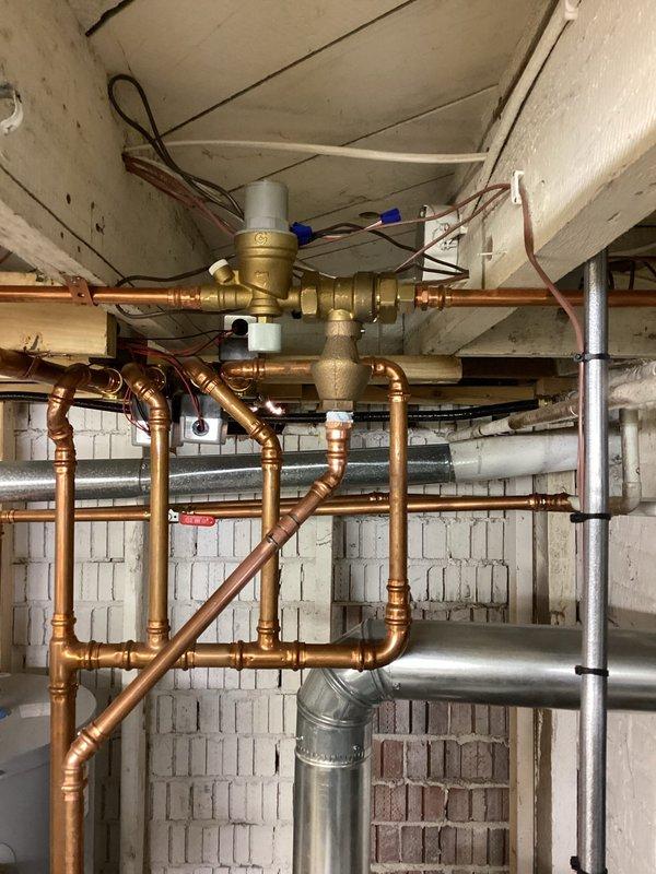 Responded to pre-sale inspection failure requiring correction of backflow preventer installation. Upon arrival, identified ASSE 1012 backflow prevention device with improper vent port configuration lacking required air gap. The vent port had a direct pipe connection, which violates code requirements for atmospheric discharge protection.

Corrected the installation by removing the direct pipe connection from the vent port fitting and establishing a proper air gap to allow atmospheric venting as mandated by ASSE 1012 standards. Verified that the backflow preventer assembly, integrated with the hydronic heating system's circulation pump and pressure monitoring equipment, now meets code compliance for the final inspection. The Taco circulator pump and associated copper piping network remained fully operational throughout the service call. System pressure verified within normal operating parameters following correction.