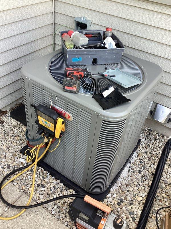 Completed installation of new air conditioning system and evaporator coil at residential property. New outdoor condensing unit was positioned on gravel pad against exterior wall with proper clearances maintained, and system was charged and tested to manufacturer's specifications with all readings within acceptable parameters.