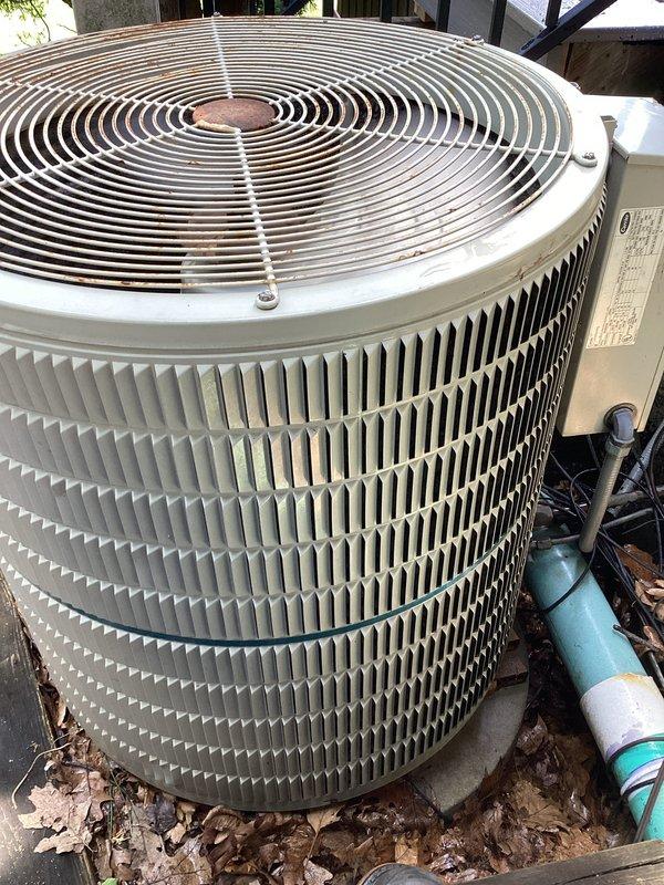 Completed comprehensive air conditioning tune-up on residential outdoor condenser unit. Performed standard maintenance inspection including visual assessment of cabinet condition, fan guard, condenser coils, and refrigerant line connections. Unit found in normal operating condition with minor debris accumulation around base, typical for exterior installation.