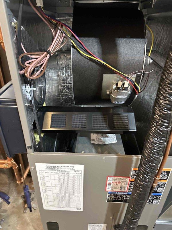 Completed installation of new air handler unit in basement location. Installed Patriot control module, connected refrigerant lines, configured electrical wiring and controls with multi-colored low-voltage connections, and integrated supply and return ductwork with flexible silver ducting. Unit tested and operational with evaporator coil assembly properly illuminated and functioning.