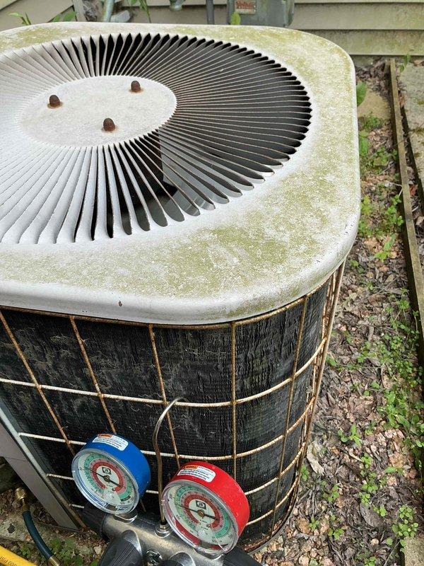 Responded to no cooling complaint on aging outdoor condensing unit. Upon arrival, connected manifold gauges to service ports and diagnosed system with low refrigerant charge due to leak. Unit showed significant weathering and biological growth consistent with age and outdoor exposure. Performed refrigerant recovery, leak detection, and system recharge to restore cooling operation.