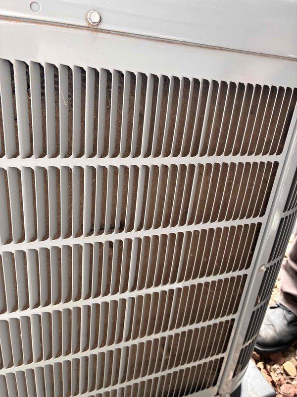 Completed comprehensive HVAC tune-up service on residential system. Inspected indoor evaporator coil compartment, noting moderate dust accumulation on finned heat exchanger and debris buildup in drain pan with visible moisture staining. Examined outdoor condenser unit coil fins, which showed dirt and environmental debris accumulation between fin spacing. Documented system conditions with photographic evidence for maintenance records.