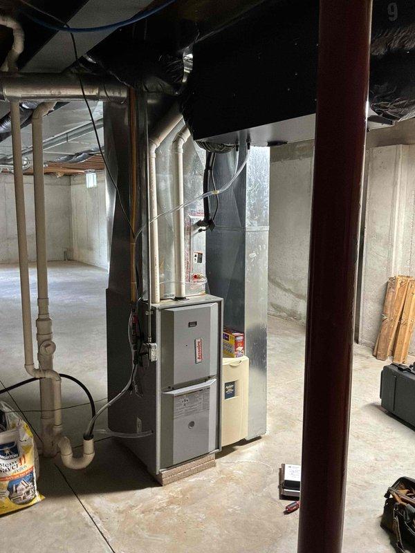 Completed air conditioning replacement estimate for residential HVAC system in basement location. Assessed existing furnace unit with overhead ductwork configuration, documented current equipment setup including beige furnace cabinet with gray electrical panel, silver metallic supply ductwork with reflective insulation, and air handler component mounted above furnace. Evaluated installation parameters for replacement AC system, reviewed electrical service capacity, inspected ductwork connections and structural support requirements. Customer approved estimate for replacement equipment installation, confirmed contact information and scheduled follow-up for installation coordination. Documented existing system configuration with photographs for replacement planning purposes.