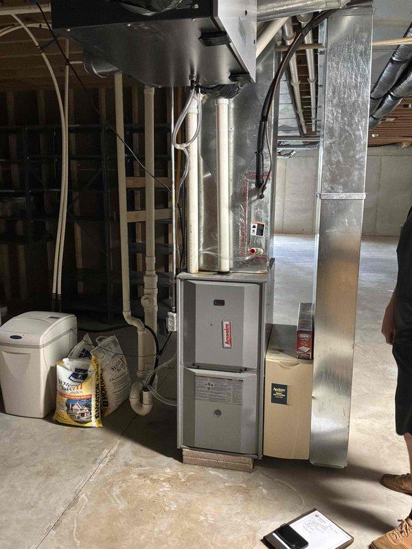 Completed air conditioning replacement estimate for residential HVAC system in basement location. Assessed existing furnace unit with overhead ductwork configuration, documented current equipment setup including beige furnace cabinet with gray electrical panel, silver metallic supply ductwork with reflective insulation, and air handler component mounted above furnace. Evaluated installation parameters for replacement AC system, reviewed electrical service capacity, inspected ductwork connections and structural support requirements. Customer approved estimate for replacement equipment installation, confirmed contact information and scheduled follow-up for installation coordination. Documented existing system configuration with photographs for replacement planning purposes.