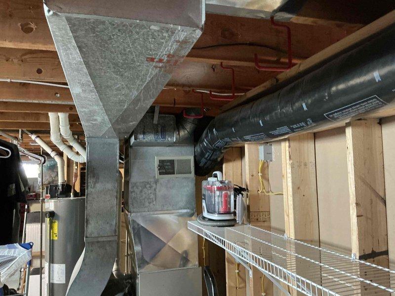 Completed on-site estimate for replacement of 28+ year old air conditioning system that was no longer maintaining adequate cooling capacity. Assessed existing HVAC equipment in basement utility area, including furnace/air handler unit, galvanized ductwork, and flexible duct runs. Evaluated outdoor condenser unit with copper fins showing age-related wear, along with associated refrigerant lines, condensate drainage system, and electrical connections. Documented current system configuration including PVC condensate piping and equipment placement over decorative rock bed. Provided replacement recommendations to restore proper cooling performance.