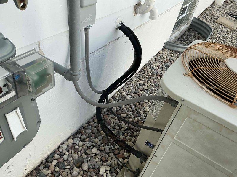 Completed on-site estimate for replacement of 28+ year old air conditioning system that was no longer maintaining adequate cooling capacity. Assessed existing HVAC equipment in basement utility area, including furnace/air handler unit, galvanized ductwork, and flexible duct runs. Evaluated outdoor condenser unit with copper fins showing age-related wear, along with associated refrigerant lines, condensate drainage system, and electrical connections. Documented current system configuration including PVC condensate piping and equipment placement over decorative rock bed. Provided replacement recommendations to restore proper cooling performance.