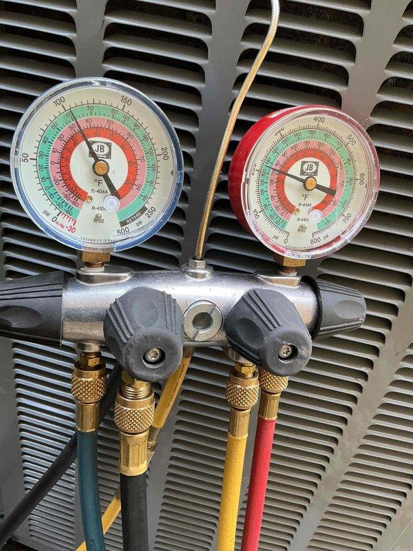 # HVAC Maintenance Report

Completed routine cooling season preventive maintenance visit per membership agreement. Performed comprehensive system inspection and diagnostic testing on residential air conditioning unit. Utilized digital clamp meter to measure electrical parameters, recording compressor amperage draw of 33.88 amps. Verified proper electrical operation and confirmed readings within manufacturer specifications.

Connected refrigerant manifold gauge set with blue low-side and red high-side gauges to service ports. Measured system pressures to evaluate refrigerant charge and overall system performance. All pressure readings fell within normal operating ranges for ambient conditions. Inspected condenser unit exterior components including coil fins, which showed good condition with no significant debris accumulation or damage. 

System operating efficiently with no deficiencies noted. All equipment functioning as designed. Preventive maintenance service completed successfully.