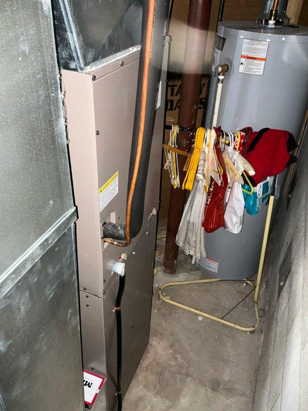Responded to emergency service call for AC system with recurring refrigerant loss—system had previously required 2lbs of refrigerant that subsequently leaked out. Performed comprehensive system evaluation and provided replacement estimate for aging HVAC equipment located in basement utility area, documenting existing furnace and associated mechanical systems for customer consideration.