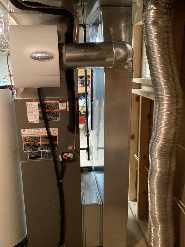 Completed full HVAC system installation including new furnace and air conditioning equipment. Installed gray cabinet furnace with PVC venting system, configured condensate drain lines with proper traps and connections, and mounted AprilAire humidifier unit to ductwork for whole-home humidity control. Connected all electrical components, ran metallic flex ductwork to distribution system, and verified proper airflow through supply and return paths. System tested and operational upon completion.