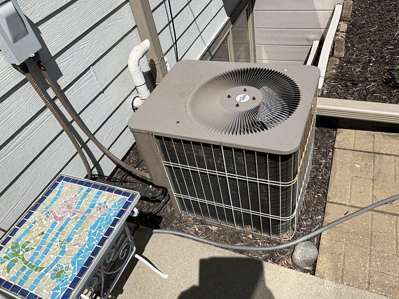 Conducted estimate for replacement of 21-year-old air conditioning system and natural gas furnace located in lower level condo. AC unit experiencing failure, running for less than one minute before shutting down, indicating end of service life. Evaluated existing outdoor condenser unit and indoor furnace installation, documented current system configuration including ductwork and drainage components, and provided replacement options for complete HVAC system upgrade.