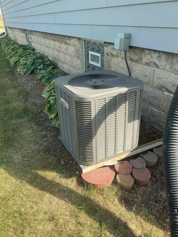 Responded to no cooling call on residential air conditioning system installed in 2013. Upon arrival, confirmed indoor blower motor operational but no cooling output from system. Performed diagnostic evaluation of outdoor condenser unit located on exterior foundation. Inspected compressor operation, refrigerant levels, electrical connections, and capacitor function. Unit positioned on wooden platform with proper clearances maintained. Electrical disconnect box verified accessible and functional. Identified root cause of cooling failure and provided customer with findings and repair recommendations to restore system operation.